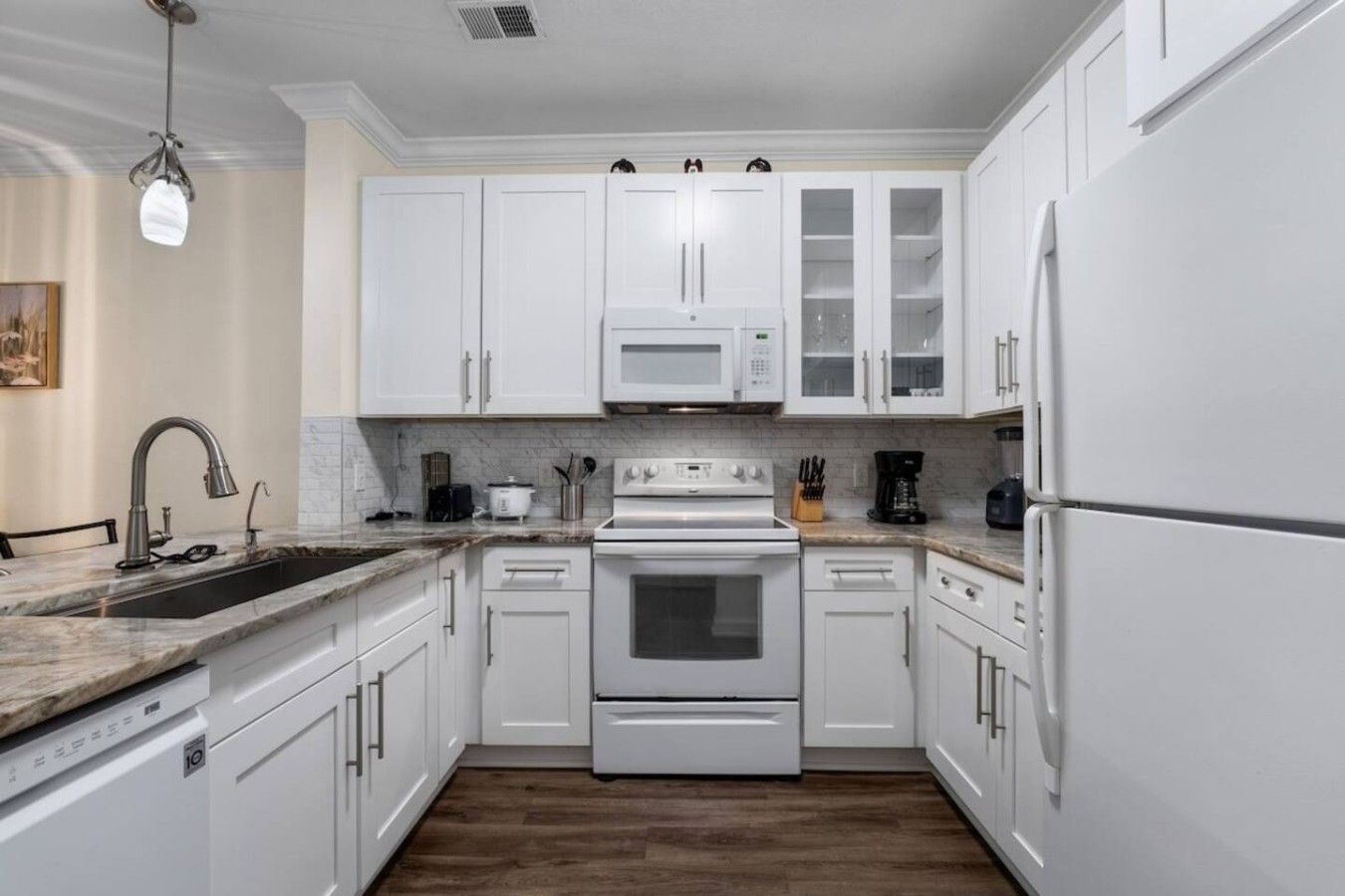 A kitchen with white cabinets, a microwave, a stove, and a refrigerator.