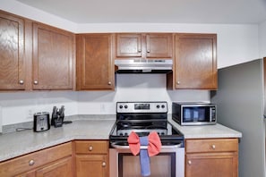 A kitchen with wooden cabinets, a stove, a microwave, and a toaster.