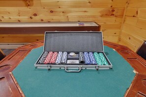 Una mesa de póker con superficie de fieltro verde y un estuche que contiene fichas de póker y un botón de crupier.