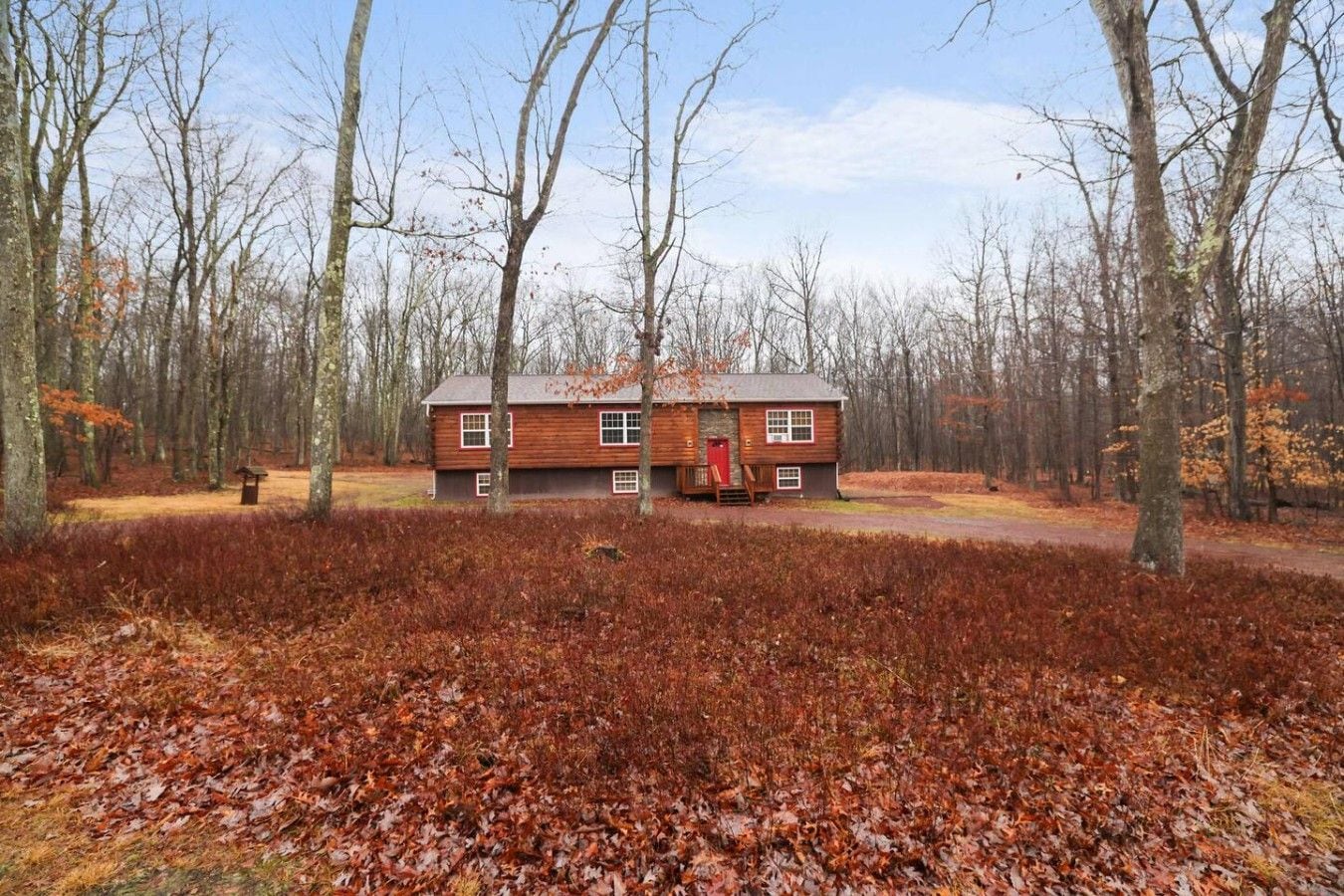 Eine Holzhütte, umgeben von einem Wald mit Herbstlaub.