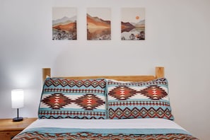 A bed with patterned pillows, a wooden headboard, and a nightstand with a lamp.