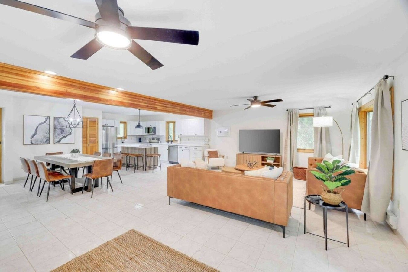 A modern living room with a sofa, dining area, kitchen, and ceiling fans.