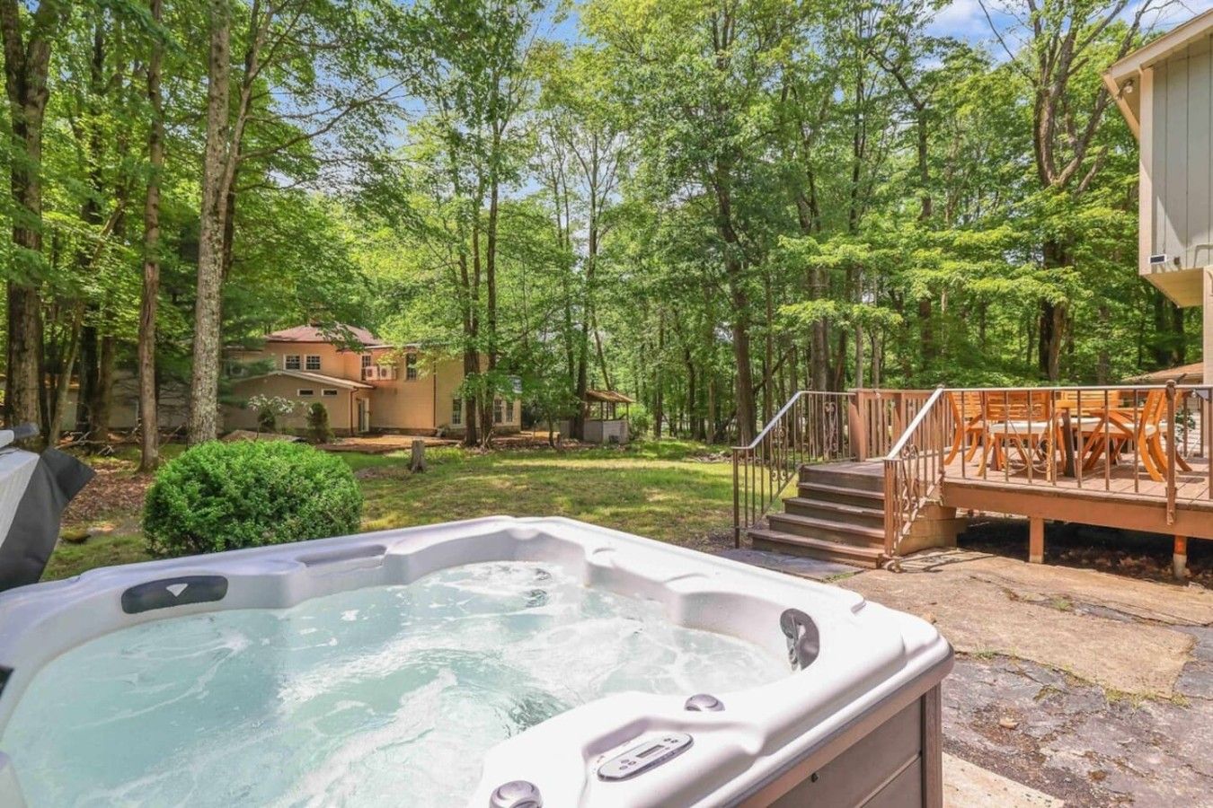 A hot tub in a backyard with a deck and stairs leading to a house.