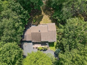 A single-story building surrounded by dense greenery, with a clear driveway leading to the entrance.