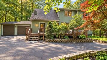 A two-story house with a garage, a front porch, and a stone retaining wall.