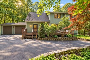 A two-story house with a garage, a front porch, and a stone retaining wall.