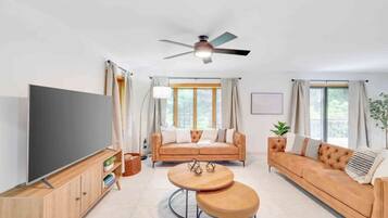 A modern living room with a sofa set, a TV, and a ceiling fan.