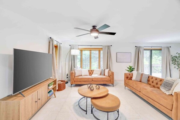 A modern living room with a sofa set, a TV, and a ceiling fan.