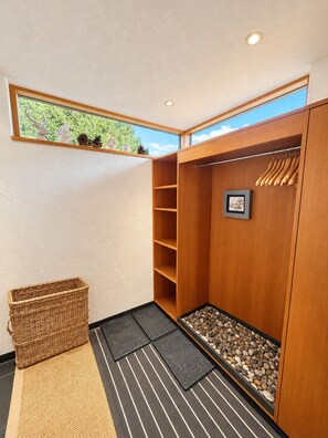A walk-in closet with wooden shelving, a hanging rod, a small framed picture, a woven basket, and a pebble tray. - Foppa Alpine Lodge – Ski-in/Ski-out & Sauna (Valbella)