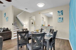 A dining area with a table set for four, surrounded by chairs. A staircase is visible in the background leading to another level. - Regal Palms Villa | Lazy River | Slides | Arcade | (Davenport)