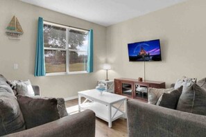 A living room with a sofa set, a coffee table, a TV mounted on the wall, and a window with curtains. - Regal Palms Villa | Lazy River | Slides | Arcade | (Davenport)