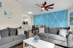 A living room with two grey sofas, a white coffee table, and a ceiling fan. - Regal Palms Villa | Lazy River | Slides | Arcade | (Davenport)