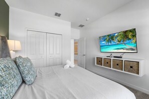 Ein Schlafzimmer mit einem Bett, einem Fernseher an der Wand und einer Tür.