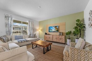 A living room with a sofa, a coffee table, a cabinet, and a painting on the wall. - 6BR Champions Gate Villa | w/Oasis Club Amenities! (Davenport)