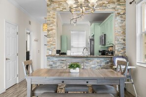 A dining area with a stone backsplash, a chandelier, and a view into the kitchen. - Regal Palms Villa | Lazy River | Slides | Games (Davenport)