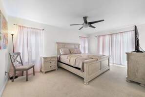 A bedroom with a bed, a chair, a nightstand, a dresser, and a ceiling fan. - Regal Palms Villa | Lazy River | Slides | Games (Davenport)