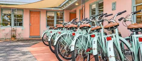 A row of numbered bicycles parked outside a building with a pink facade and a covered entrance.