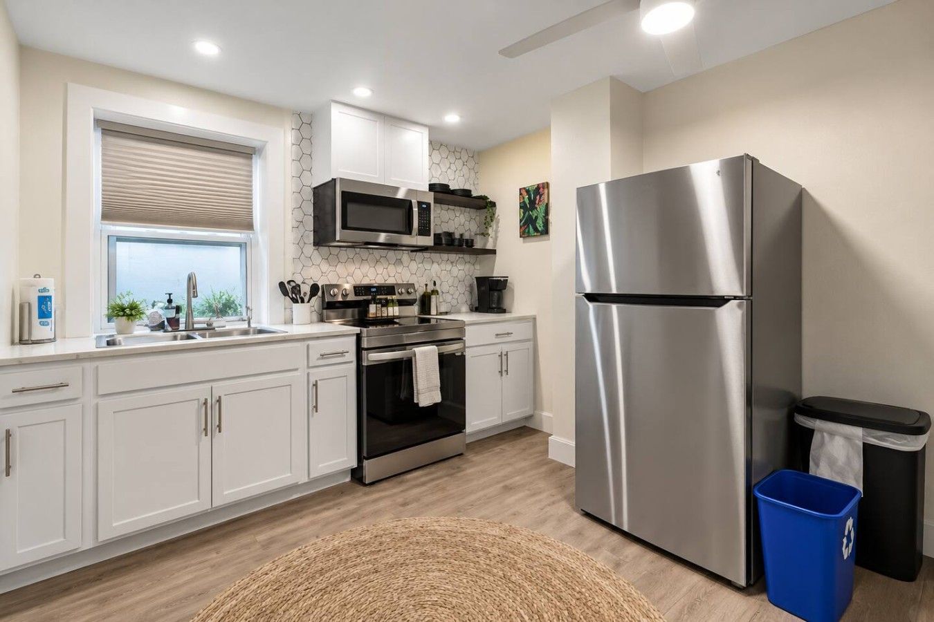 A modern kitchen with white cabinets, stainless steel appliances, a microwave, oven, and a refrigerator.