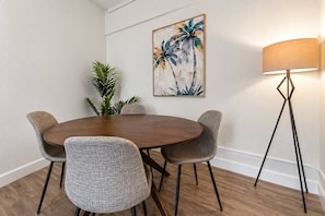Un'area pranzo con un tavolo rotondo, quattro sedie, una lampada da terra e un quadro appeso al muro.