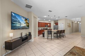 A modern kitchen with a central island, wooden cabinets, and a dining area with bar stools. - 4BR Disney Getaway | Private Pool (Kissimmee)