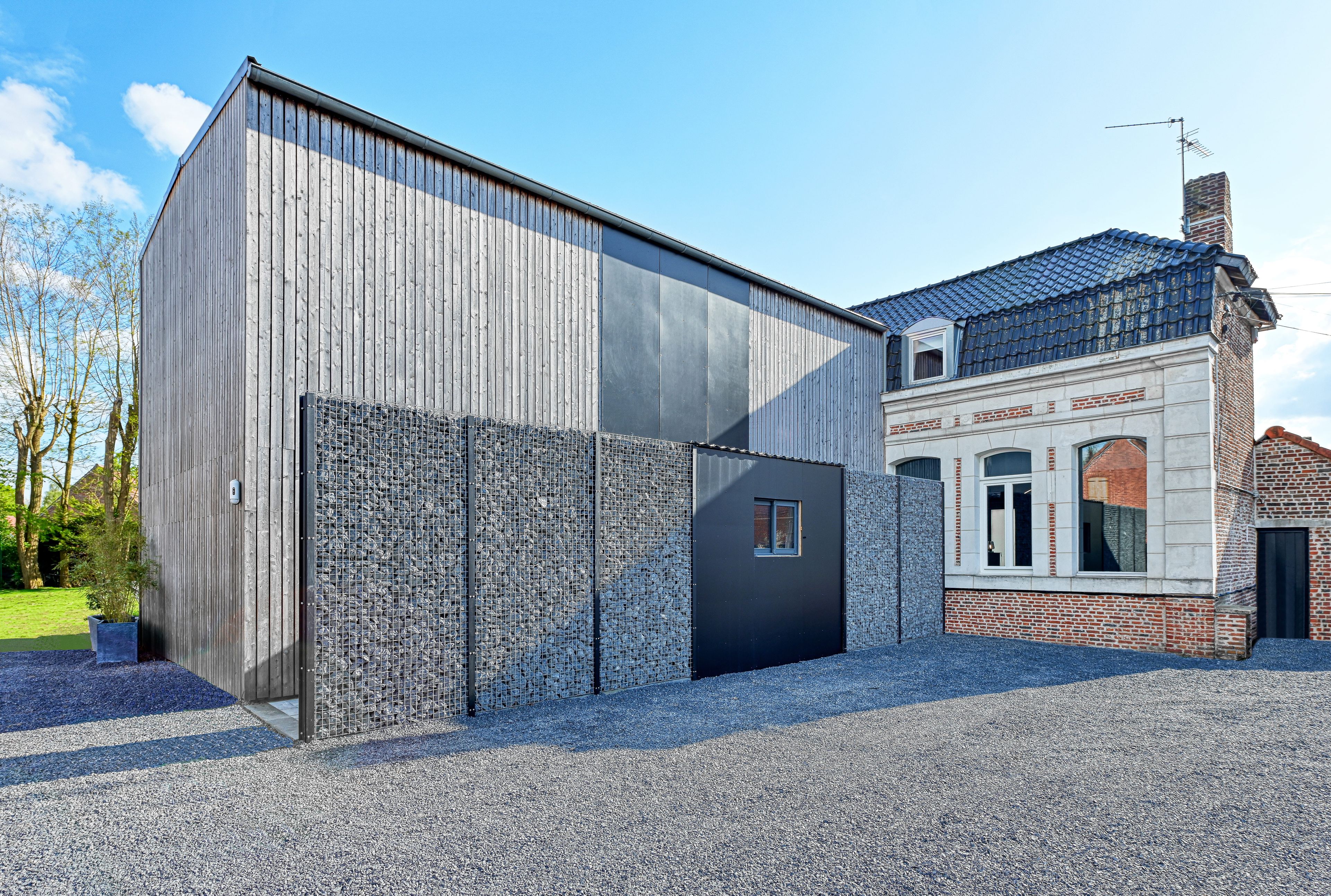 Ein modernes Gebäude mit einer großen Metallfassade und einem traditionellen Backsteinbau mit Ziegeldach.