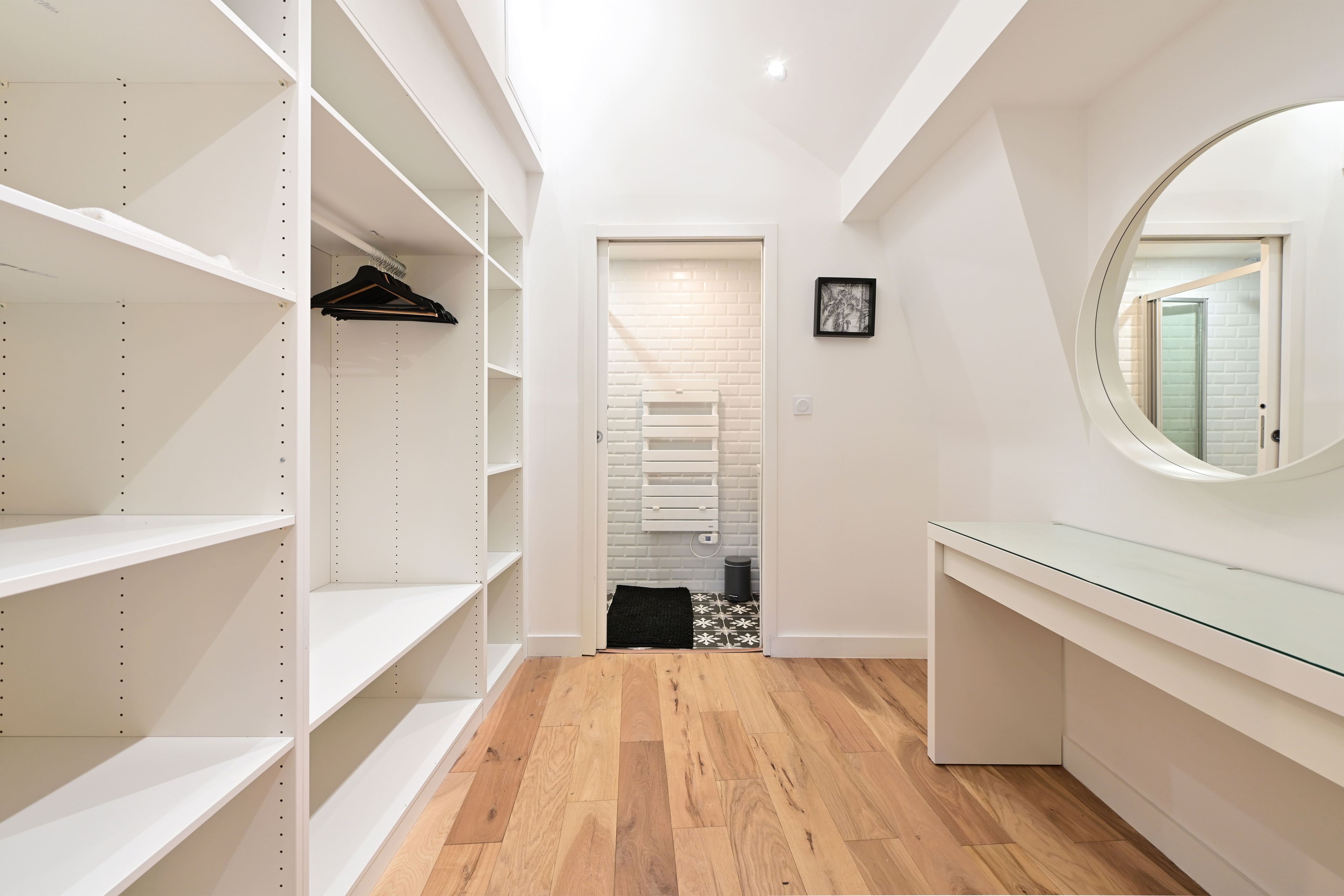 Een gang met een houten vloer, witte muren en een witte deur naar een badkamer.