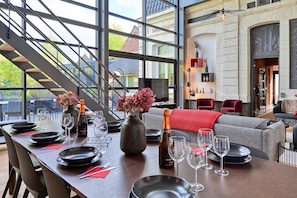Un comedor con una mesa lista para una comida, una escalera y una zona de estar con una manta roja.