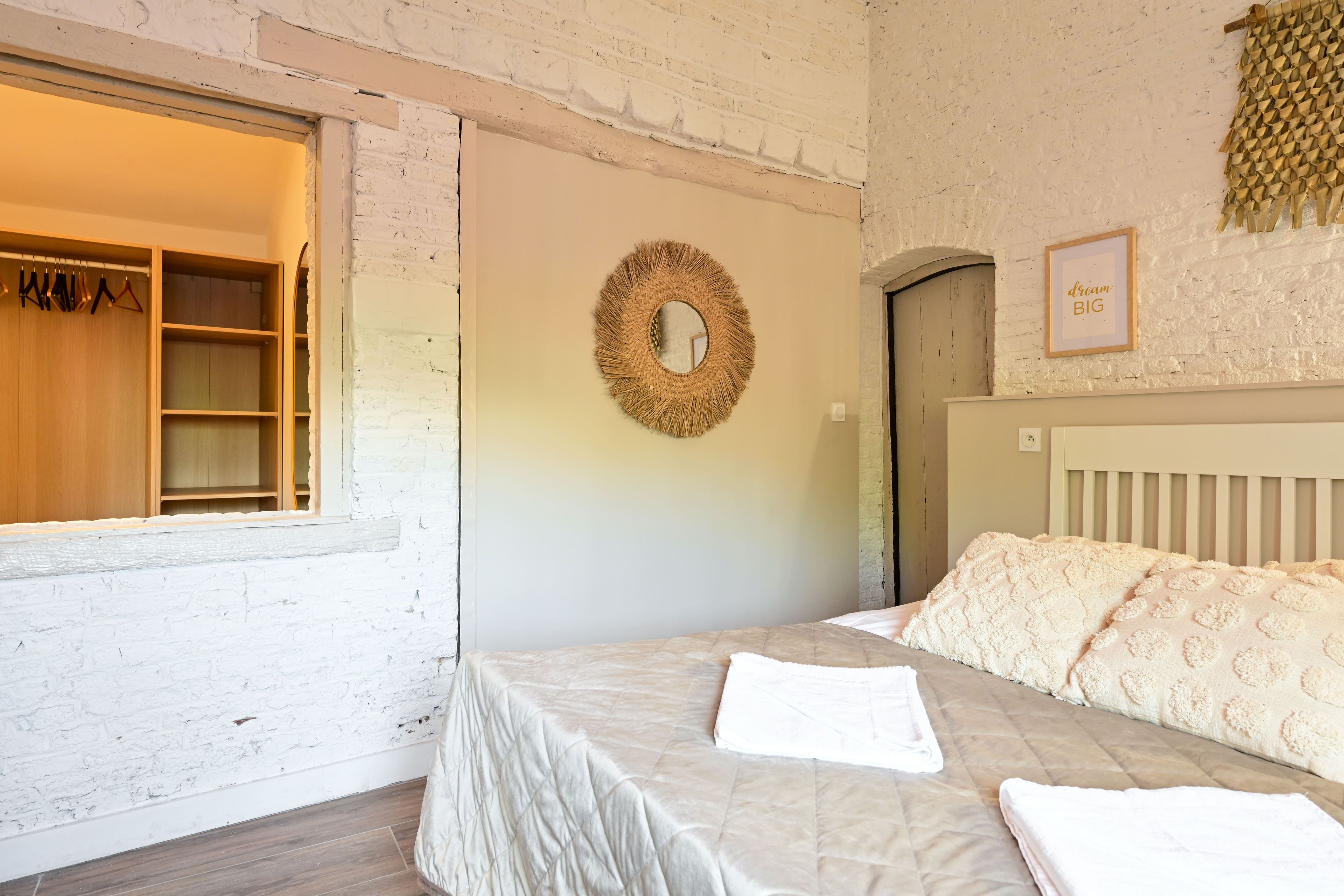 Ein Schlafzimmer mit Bett, Kleiderschrank, Spiegel und Tür.