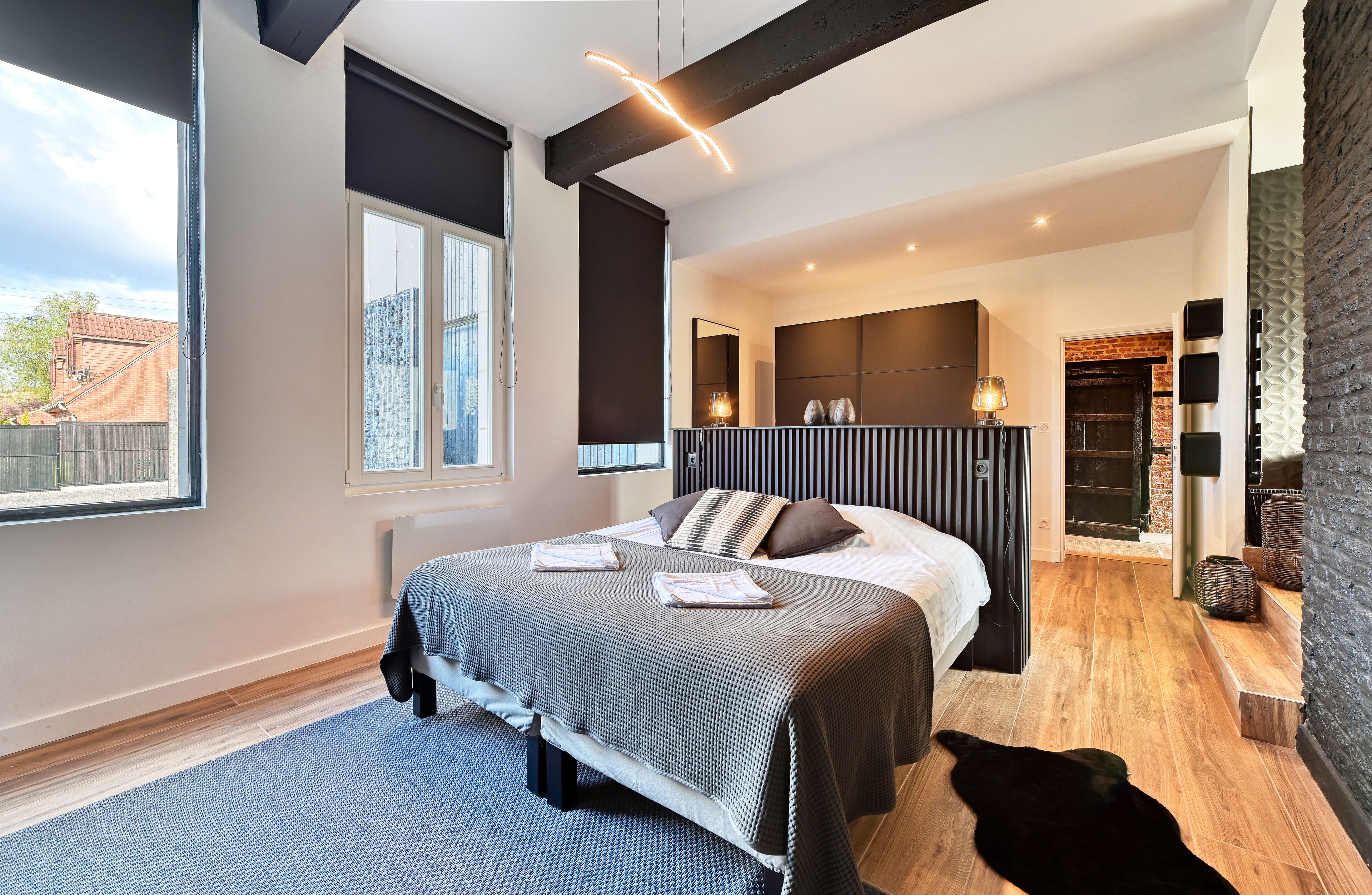 A modern bedroom with a large bed, a window, and a fireplace.
