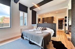 Un dormitorio moderno con una cama grande, una ventana y una chimenea.