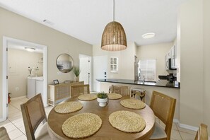 A dining area with a round table, woven placemats, and wicker chairs. - Retreat to Crystal Cove | Near Parks | Amenities (Kissimmee)