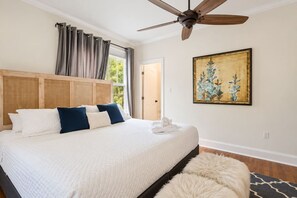 Una camera da letto con un letto grande, una ventola a soffitto, un quadro e vista sull'esterno.