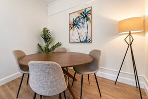 Zona pranzo con tavolo rotondo, quattro sedie, una lampada da terra e un quadro appeso al muro.