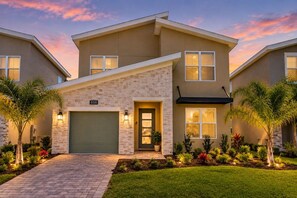 A modern two-story house with a brick facade, a garage, and a well-maintained lawn with palm trees. - Private Pool & Spa Villa | ChampionsGate (Kissimmee)