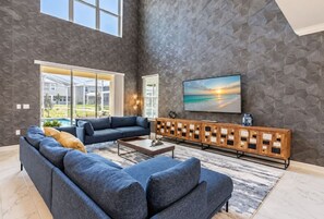 A modern living room with a large sectional sofa, a coffee table, and a wooden console. - Private Pool & Spa Villa | ChampionsGate (Kissimmee)
