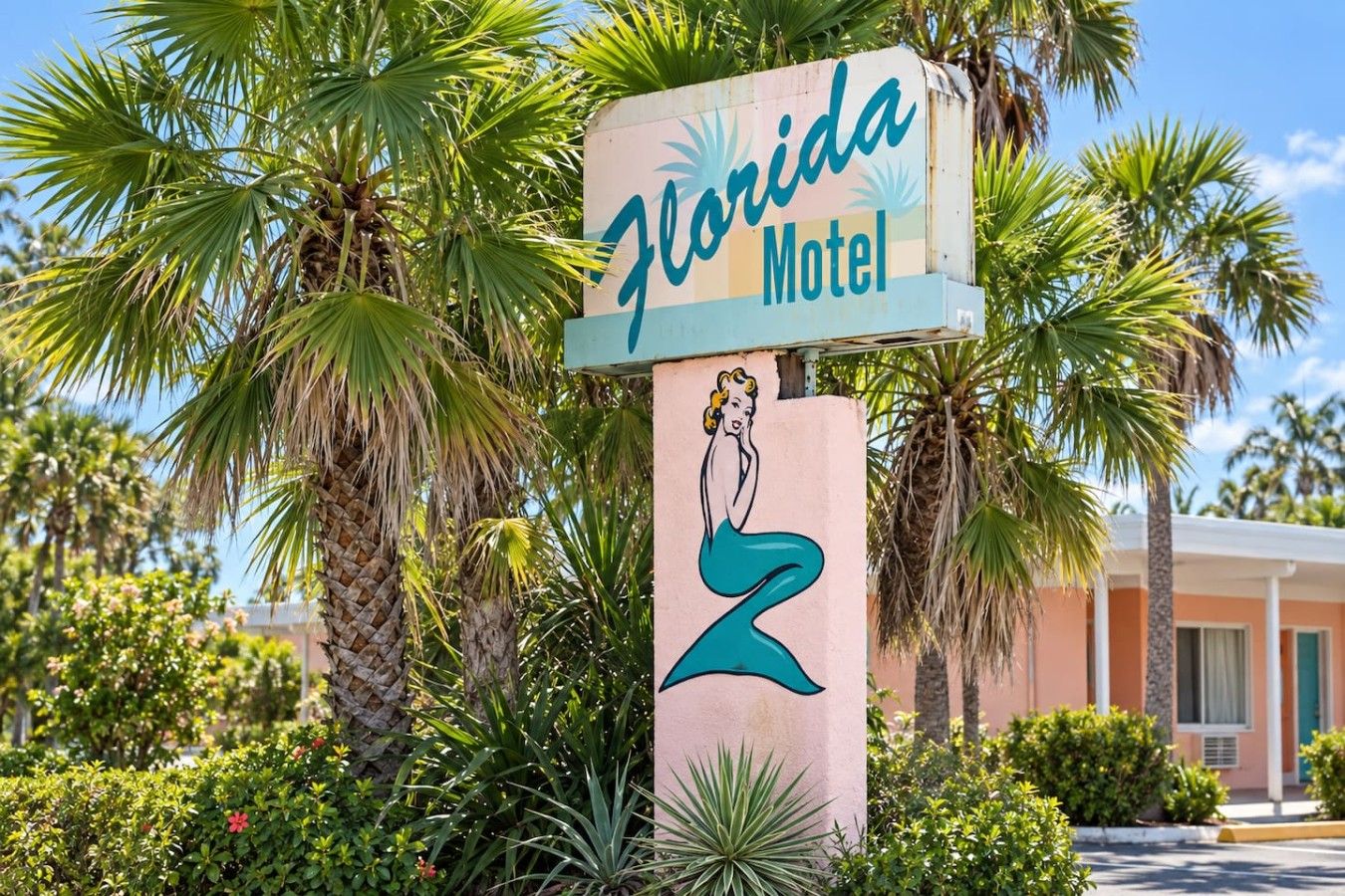 A Florida Motel sign with a stylized woman illustration, surrounded by palm trees and greenery.