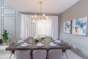 A dining room with a long table set for a meal, a chandelier, and artwork on the walls. - Relaxing Getaway | Private Pool & Spa (Kissimmee)