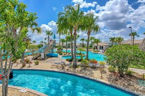 A resort pool area with multiple swimming pools, palm trees, and a slide. - Relaxing Getaway | Private Pool & Spa (Kissimmee)