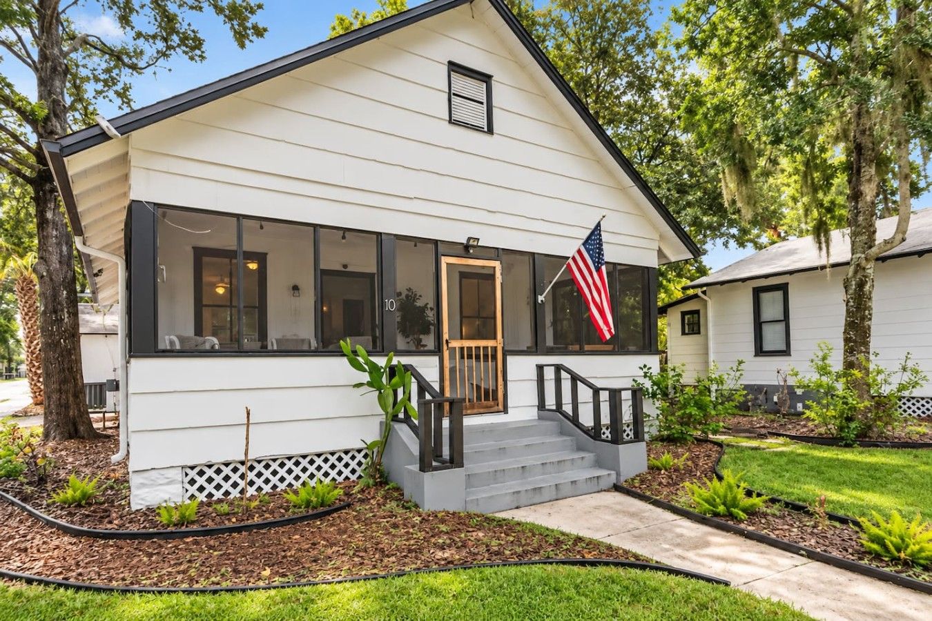 A single-story house with a front porch, a flag, and a mailbox.