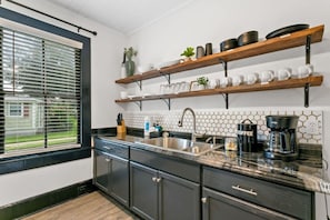A modern kitchen with a dishwasher, a coffee maker, and a window with blinds. - St. Augustine Beach Getaway | Prime Location (St. Augustine)