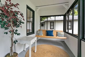A covered porch with a wooden bench, a small table, and a potted plant. - St. Augustine Beach Getaway | Prime Location (St. Augustine)