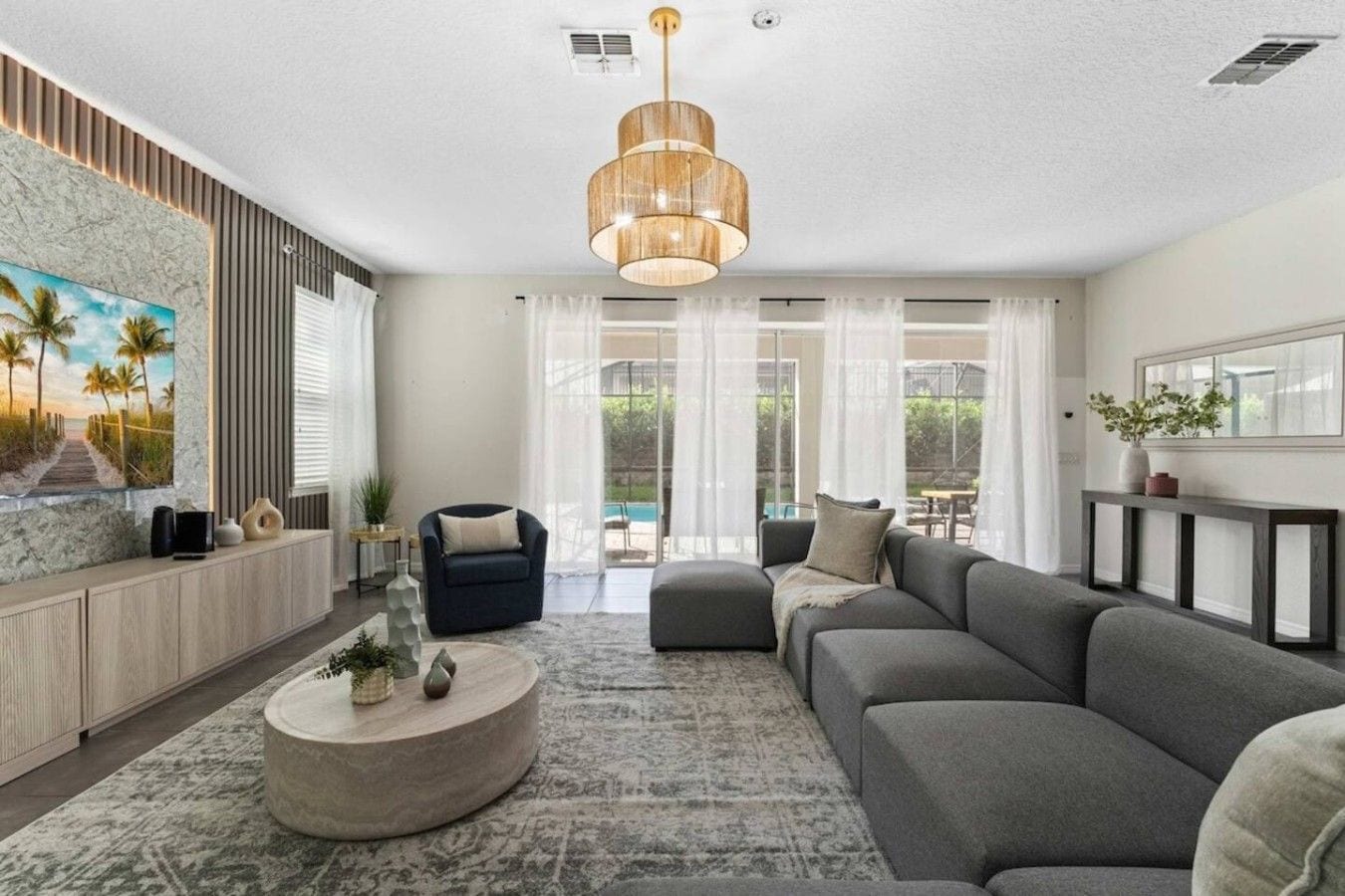 A modern living room with a sectional sofa, a round coffee table, and a large painting of a beach scene.