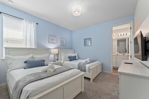A bedroom with two beds, a vanity with a mirror, and a television. - SUPER DREAM – Luxury Poolside Loft | Pool & Games (Kissimmee)