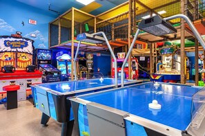 An indoor arcade with multiple gaming machines, including a table tennis table and a Cannonball Blast game. - Regal Palms Villa | Sliding Fun | Arcade | River (Davenport)