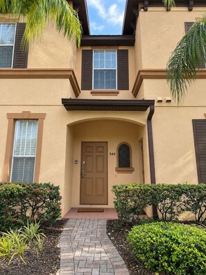 A two-story building with a beige facade, dark shutters, and a number '344' on the door. - Regal Palms Villa | Sliding Fun | Arcade | River (Davenport)