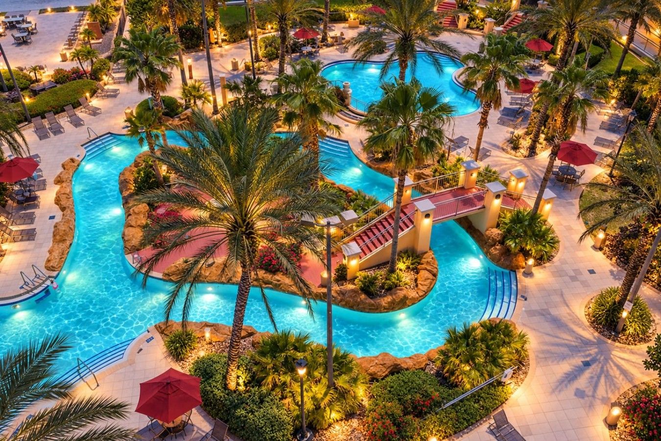 A resort with multiple swimming pools, palm trees, and outdoor seating areas.