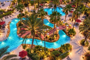 Un resort con varias piscinas, palmeras y zonas de estar al aire libre.
