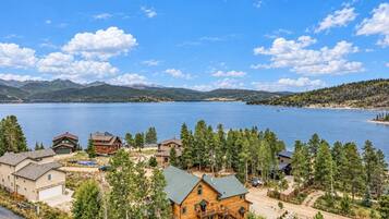 A lakeside property with multiple cabins and a large wooden house, surrounded by trees and mountains.