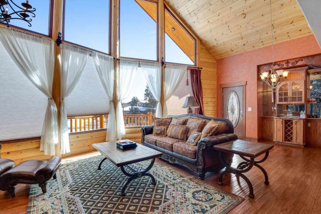 A cozy room with a wooden ceiling, a sofa, a coffee table, and a patterned rug.