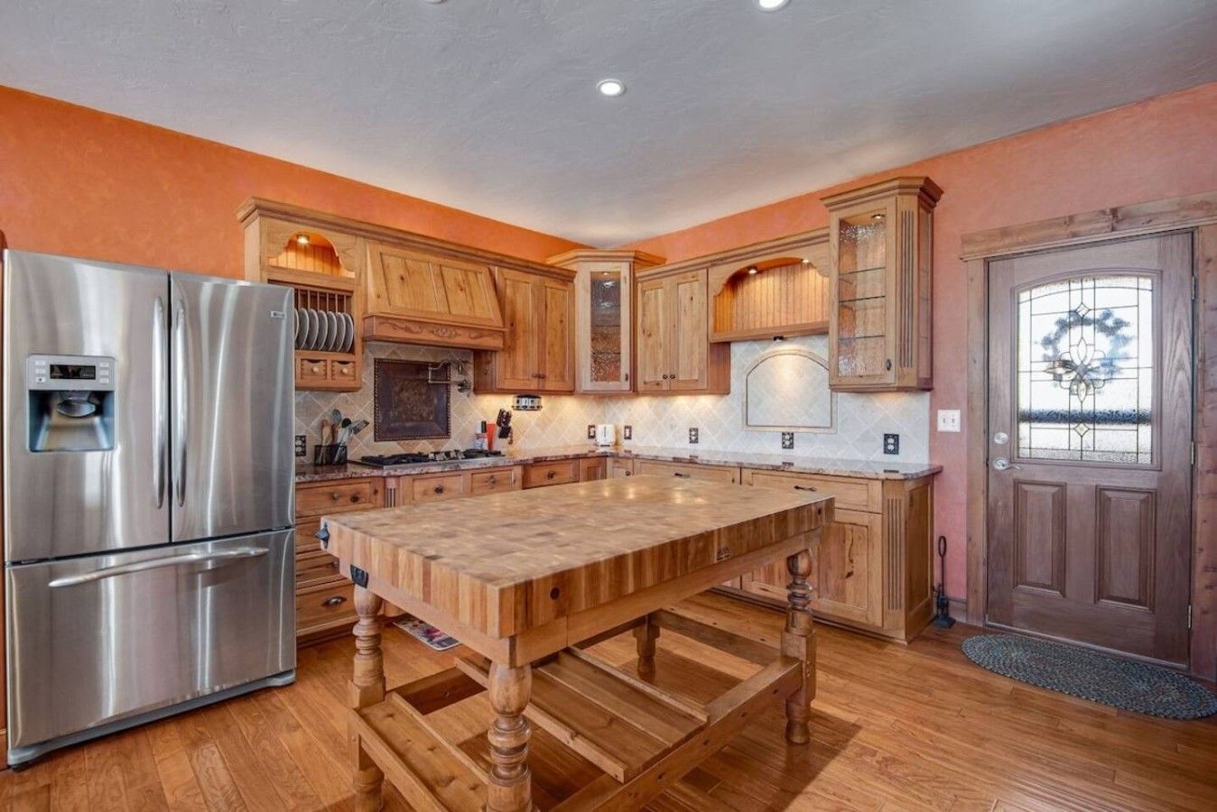 A kitchen with wooden cabinets, a stainless steel refrigerator, and a central island.